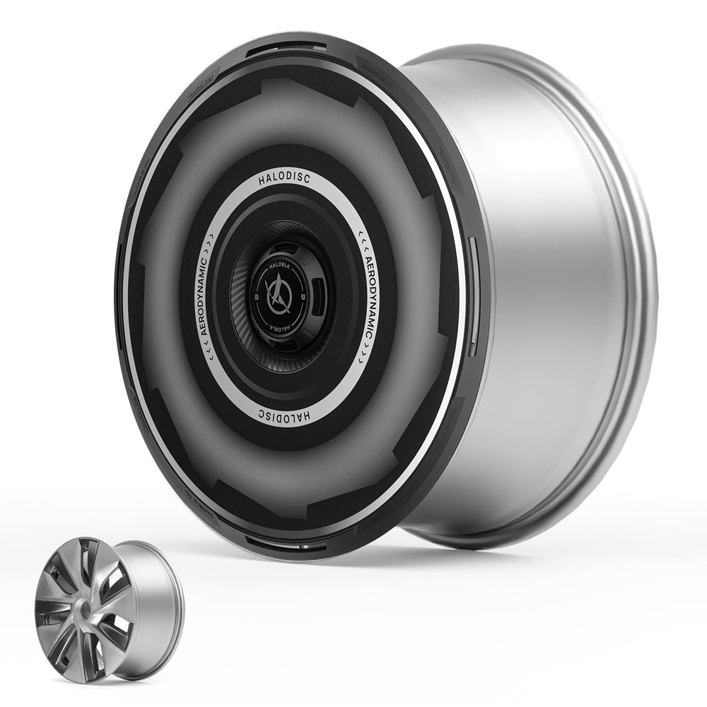 A large, futuristic silver Tesla Model 3 wheel (2017–2018) with a black HALODISC 2 aerodynamic cover from HALOBLK Store is displayed beside a standard wheel, showcasing the Vision-GT design differences.