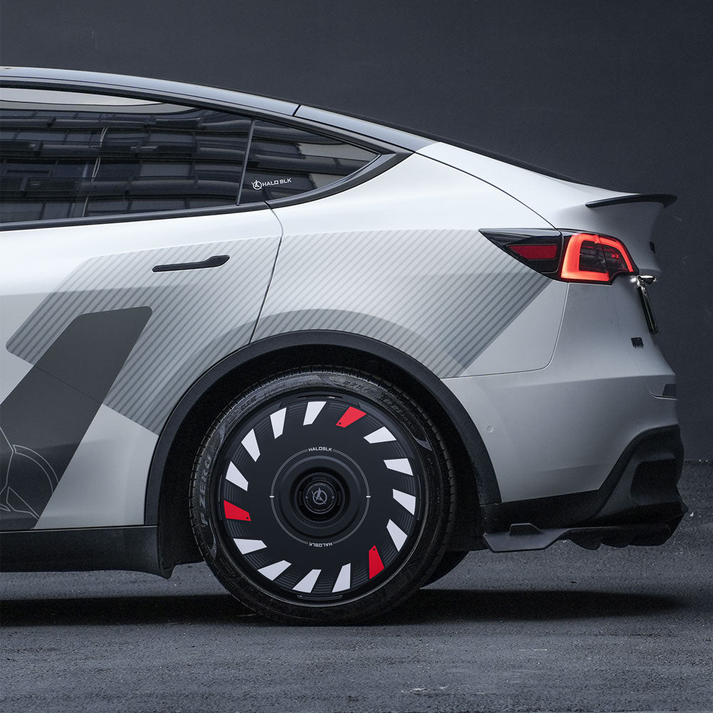 Side view of a silver Tesla Model Y with HALODISC 2 Wheel Covers by HALOBLK Store, featuring a turbo-inspired design in black, white, and red on 20" Induction Wheels. The background is dark and minimalistic.