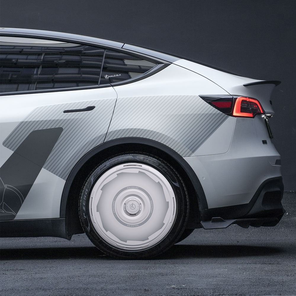A close-up side view shows HALODISC 2 Wheel Covers for Tesla Model Y 20" Induction Wheels by HALOBLK Store, featuring a futuristic silver car design with large, sleek white wheel covers, parked against a dark background.