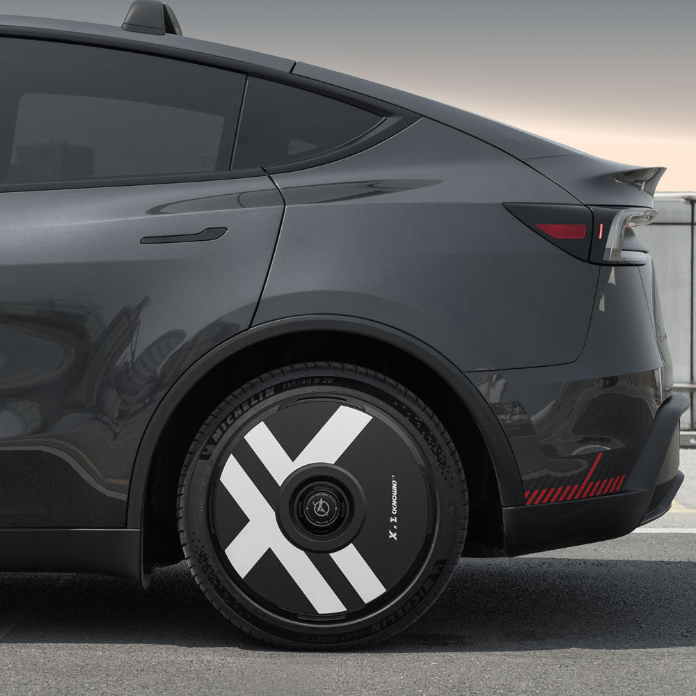 Close-up of a Tesla Model Y Juniper 20" Helix 2.0 wheel fitted with a HALODISC 2 X-Factor wheel cover by HALOBLK Store, featuring bold white diagonal stripes. The gray car’s rear and taillight are visible in the shot.