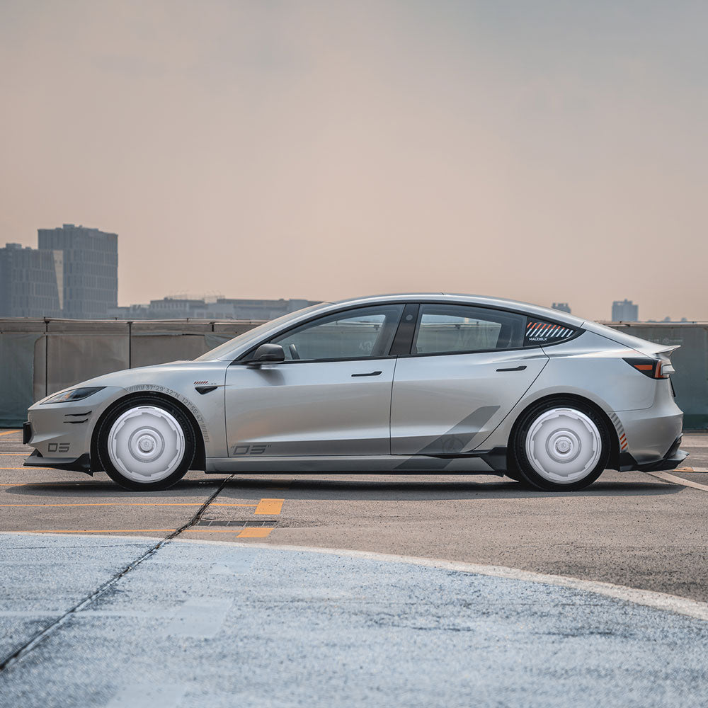 A Tesla Model 3 Highland with Vision-GT HALODISC 2 wheel covers from HALOBLK Store is parked on a rooftop, featuring white wheel covers and dark tinted windows against a city backdrop.