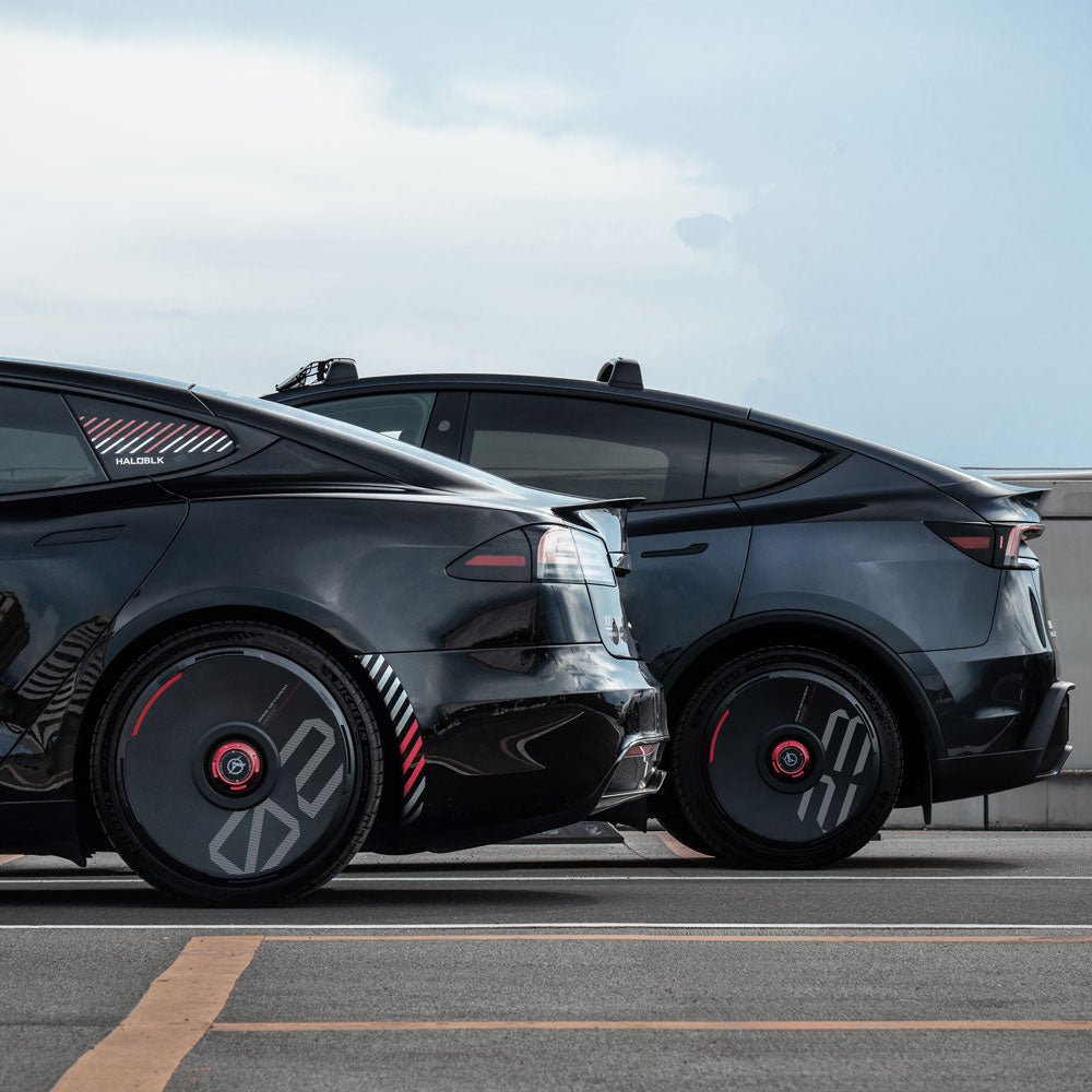 Two black Tesla cars parked side by side outdoors, each featuring HALODISC 2 Wheel Covers for Tesla (Black) from HALOBLK Store, with custom number options and showcasing a modern, futuristic design under a clear sky.