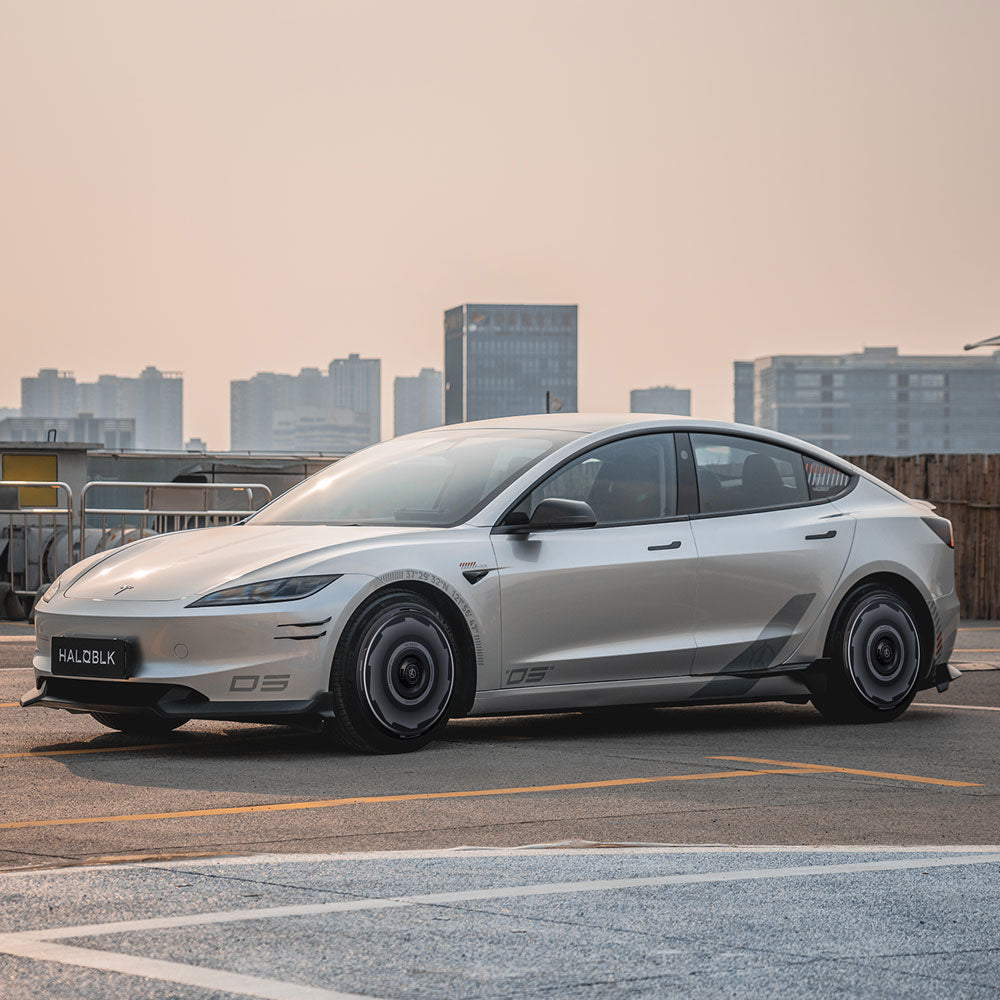 A sleek Tesla Model 3 Highland with HALODISC 2 Wheel Covers by HALOBLK Store on its 19" Nova Wheels is parked on a rooftop overlooking the city, featuring a sporty silver design and a license plate reading HALOL8K.