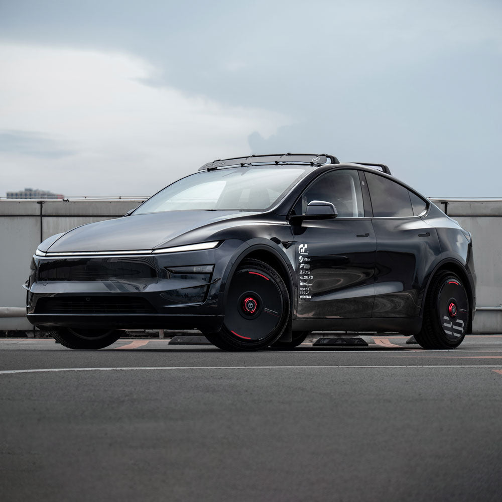 A sleek black Tesla equipped with HALODISC 2 Wheel Covers by HALOBLK Store is parked outdoors on pavement, featuring rooftop rails against a cloudy urban backdrop.