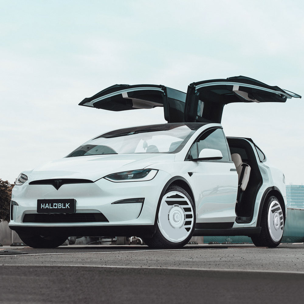 A white Tesla Model X (2021-2025) with HALODISC 2 Wheel Covers by HALOBLK Store on 20" Perihelix wheels, falcon-wing doors open, parked on a rooftop showcasing modern, sleek design.