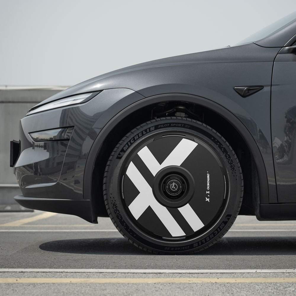 Close-up of a Tesla Model Y with Juniper 20" Helix 2.0 wheels, showcasing HALODISC 2 Wheel Covers by HALOBLK Store, featuring bold white geometric patterns and sleek lines under a clear sky.