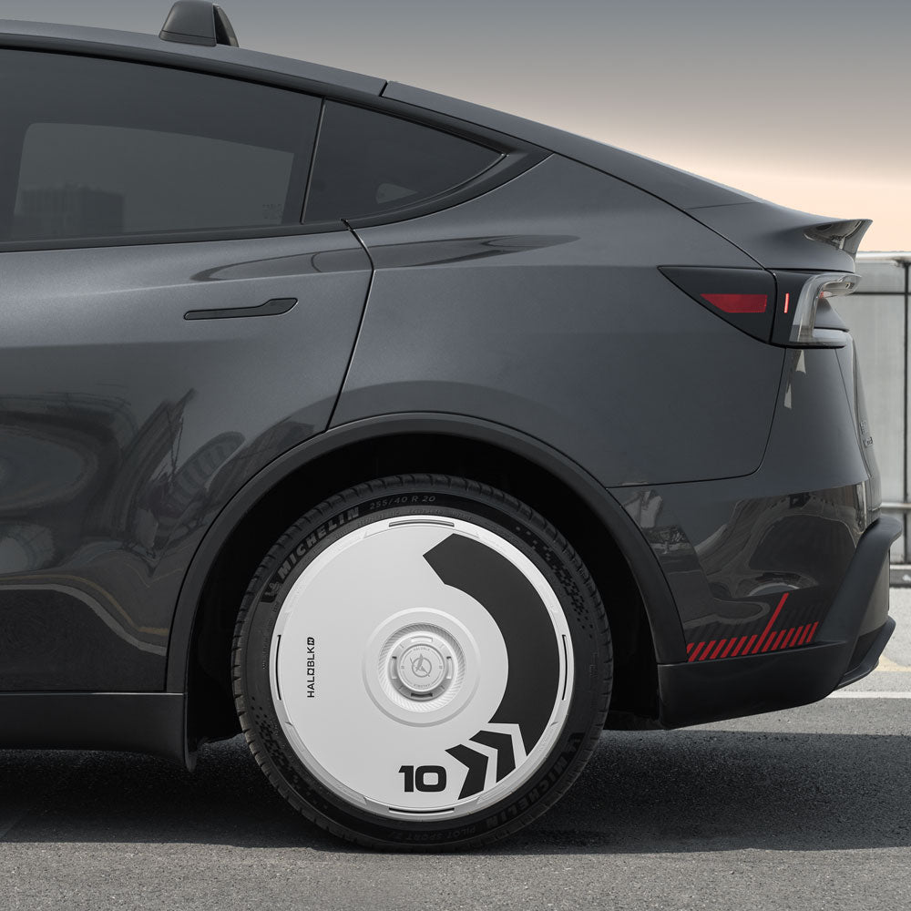 A close-up side view of a dark gray Tesla Model Y with HALODISC 2 Wheel Covers (Arrow design) from HALOBLK Store, featuring white covers with black geometric patterns on Juniper 20" Helix 2.0 Wheels.