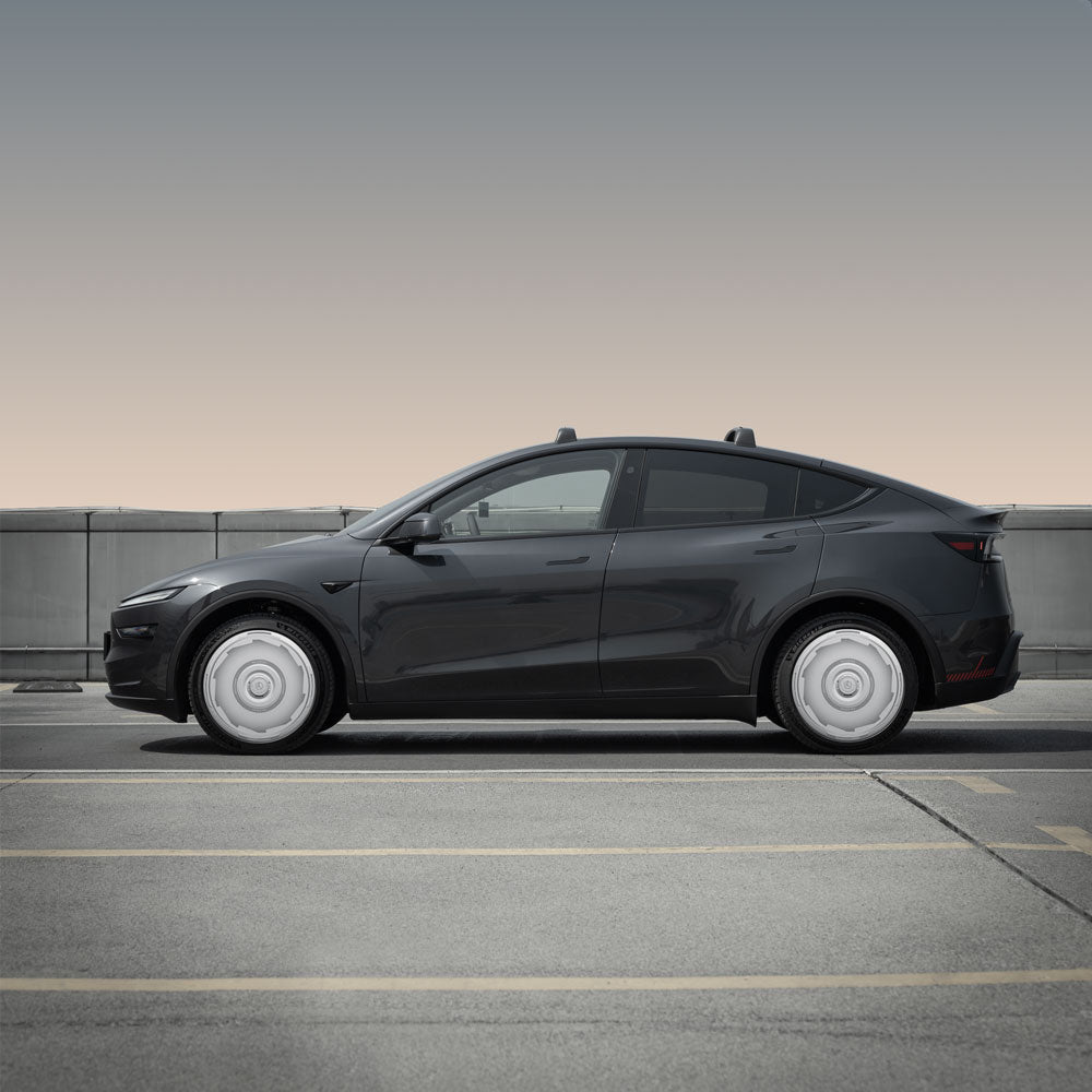 A Tesla Model Y with HALODISC 2 Wheel Covers by HALOBLK Store is parked in an empty outdoor lot, viewed from the side, gray wheel covers on 20" Helix 2.0 wheels, with a concrete barrier and gradient sky in the background.