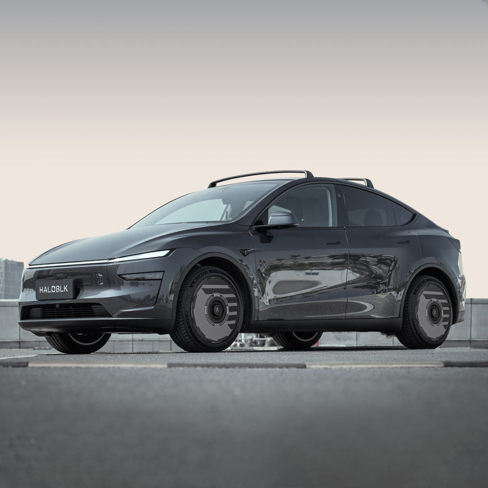 A sleek black Tesla Model Y with HALODISC 2 Wheel Covers for 19" Juniper Crossflow Wheels by HALOBLK Store is parked outdoors on a concrete surface, showcasing modern design, smooth lines, and stylish dark rims.