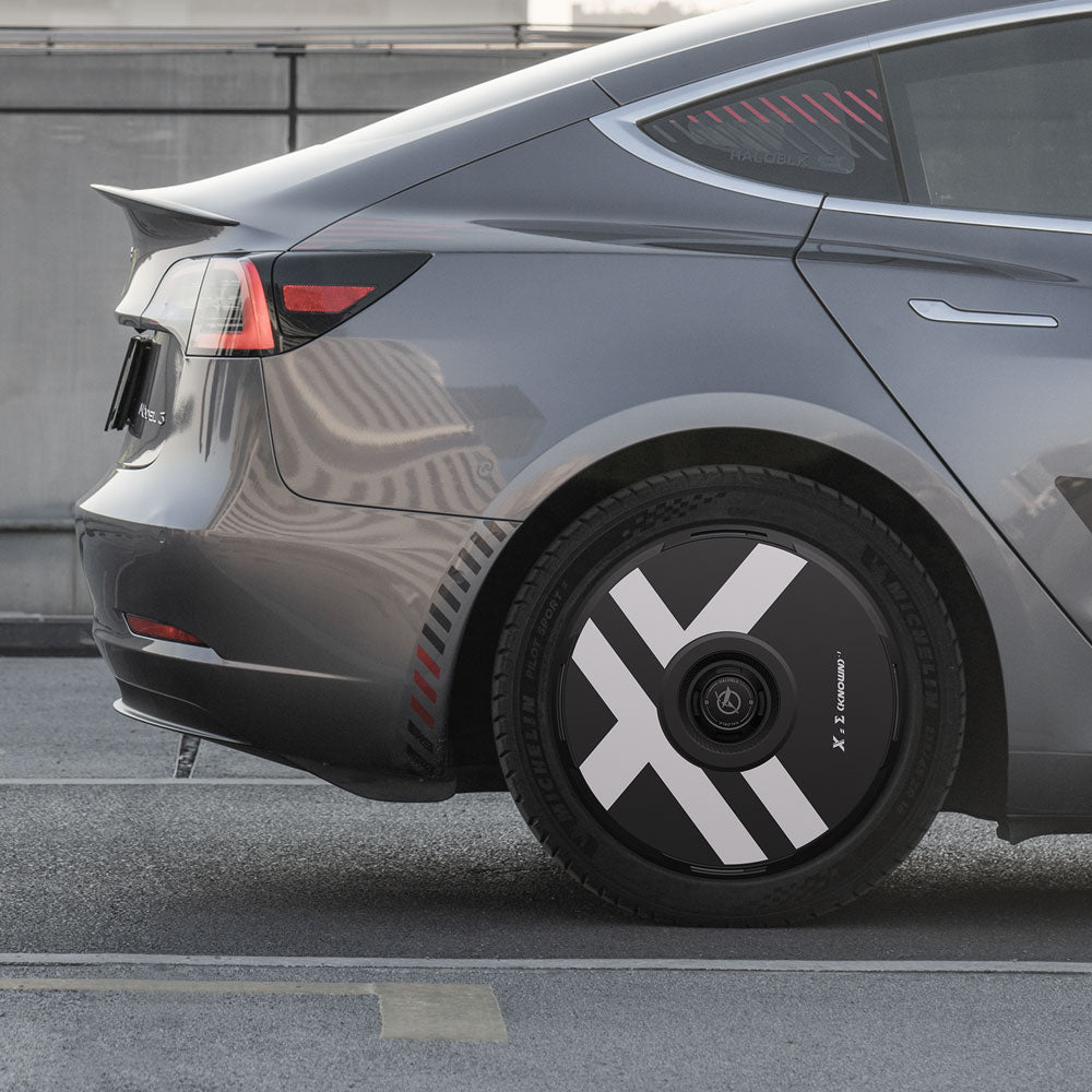 Close-up of a gray Tesla Model 3 (2017-2018) parked outdoors, showcasing HALODISC 2 Wheel Covers (HALOBLK Store) with bold white diagonal stripes on black, designed for 19" Performance Wheels. Urban background.