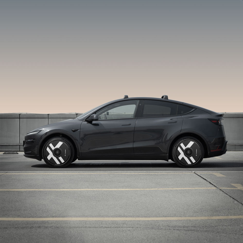 A black Tesla Model Y with HALODISC 2 Wheel Covers (Helix 2.0, X-Factor) from HALOBLK Store parked in an empty rooftop lot, featuring modern geometric hubcaps and a muted sky in the background.