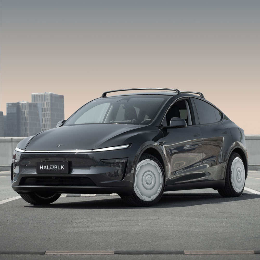 A Tesla Model Y with HALODISC 2 Wheel Covers (Juniper 20" Helix 2.0, Vision-GT) from the HALOBLK Store is parked on a rooftop against a city backdrop, its license plate reading HALOBLK. The sleek design stands out under the clear sky.