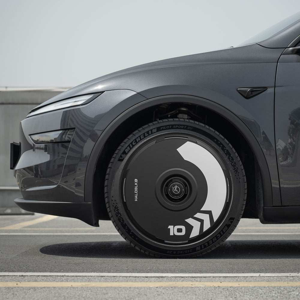 Close-up side view of a gray car with HALODISC 2 Wheel Covers for Tesla Model Y Juniper 20" Helix 2.0 Wheels by HALOBLK Store, featuring a black and white geometric Arrow design and the number 10 displayed on the cover.