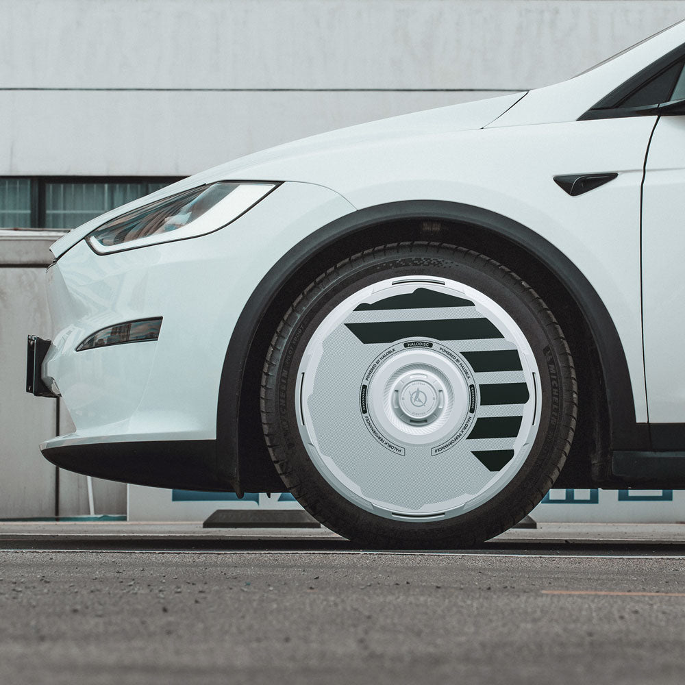 Side view of a white Tesla Model X (2021-2025) with HALODISC 2 20" Perihelix Wheel Covers by HALOBLK Store, showcasing a futuristic, sleek design. A modern building with windows appears in the background.