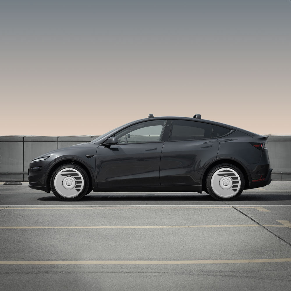 A black Tesla Model Y with HALODISC 2 Wheel Covers for Juniper 19" Crossflow Wheels (by HALOBLK Store) is parked in an empty outdoor lot against a concrete barrier, viewed from the side with a gradient sky in the background.