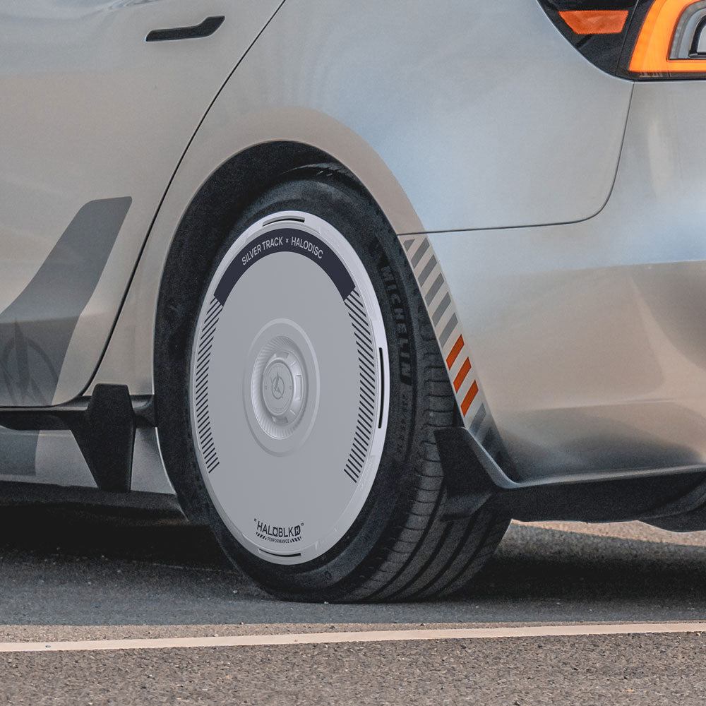 Close-up of a silver Tesla Model 3 Highland 20" Warp Wheel with HALODISC 2 Wheel Cover by HALOBLK Store, featuring sleek circular detailing and orange stripes above the wheel.