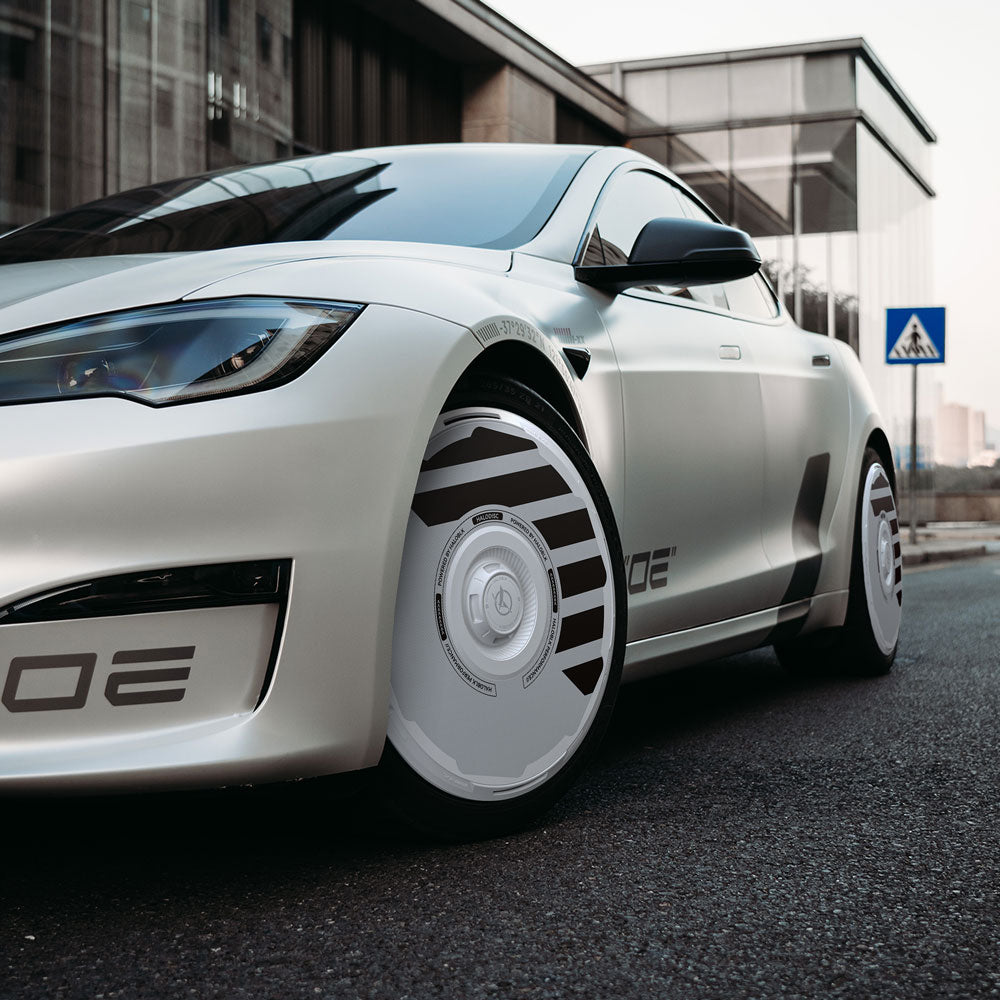 A Tesla Model S with HALODISC 2 Wheel Covers by HALOBLK Store, featuring smooth, solid 19" Slipstream wheels, is parked near a glass building and a pedestrian crossing sign on a city street.
