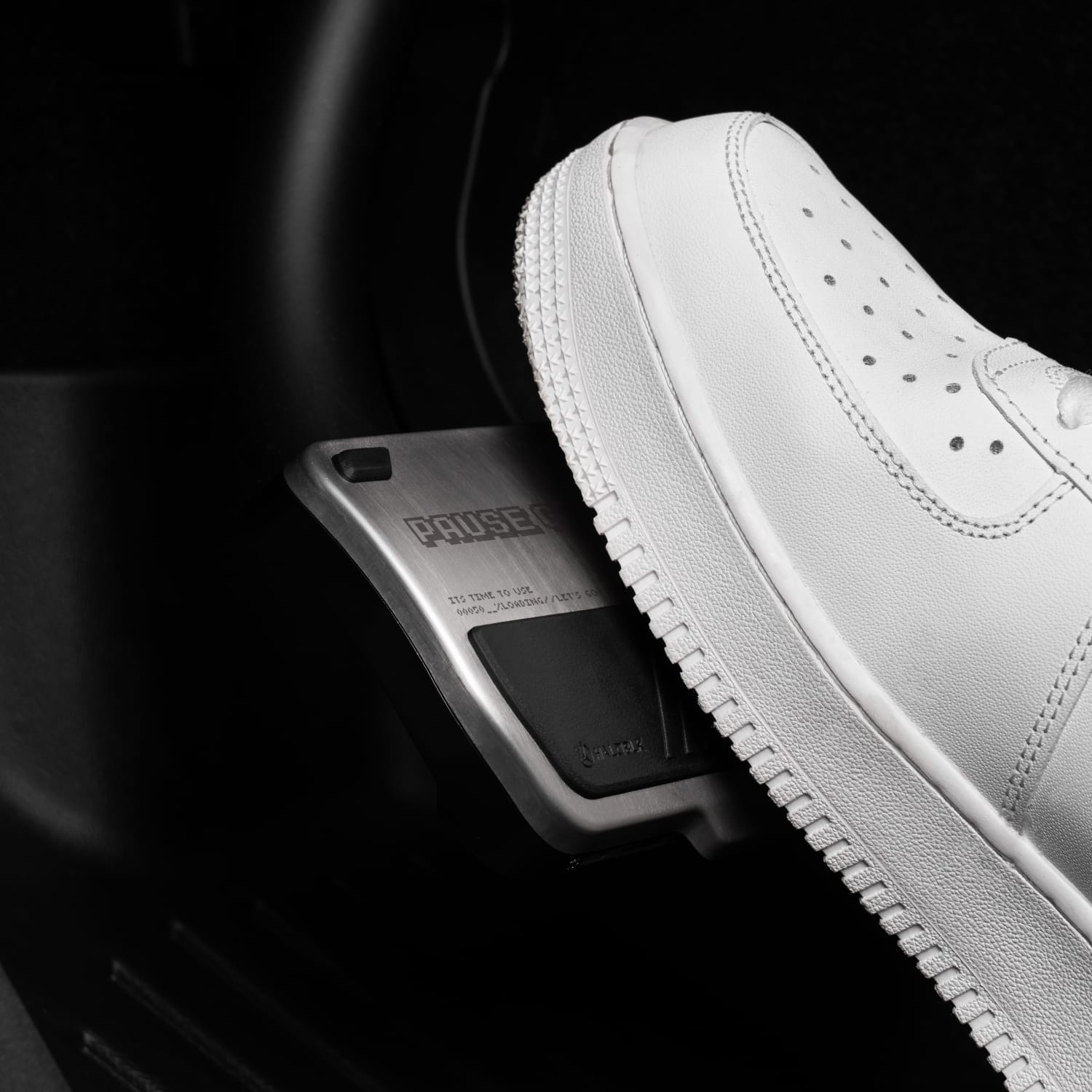 A close-up of a white sneaker pressing the Alloy Pedals 2 for Tesla by HALOBLK Store, labeled "PULSE," inside a vehicle. Focus is on the shoe and the ArcadeKid pedal mechanism.