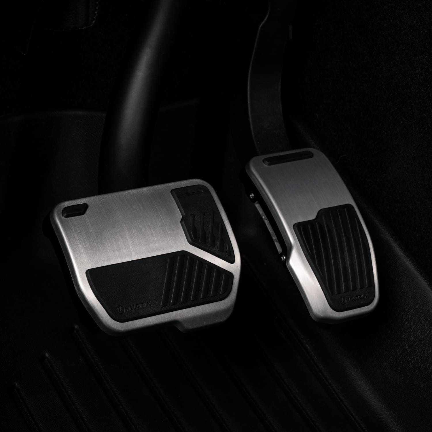 Close-up of Alloy Pedals 2 for Tesla by HALOBLK Store, featuring brushed metal finish and black rubber grips, set against a dark interior floor mat.
