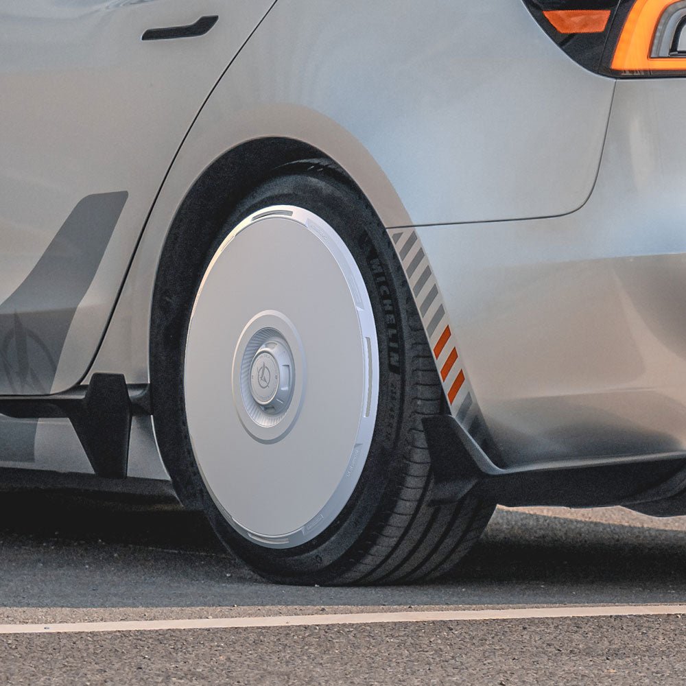 Close-up of a Tesla Model 3 Highland fitted with HALODISC 2 Wheel Covers for 20" Warp Wheels by HALOBLK Store, featuring a sleek, minimalist design and Michelin tire. The silver car is parked on a paved surface.