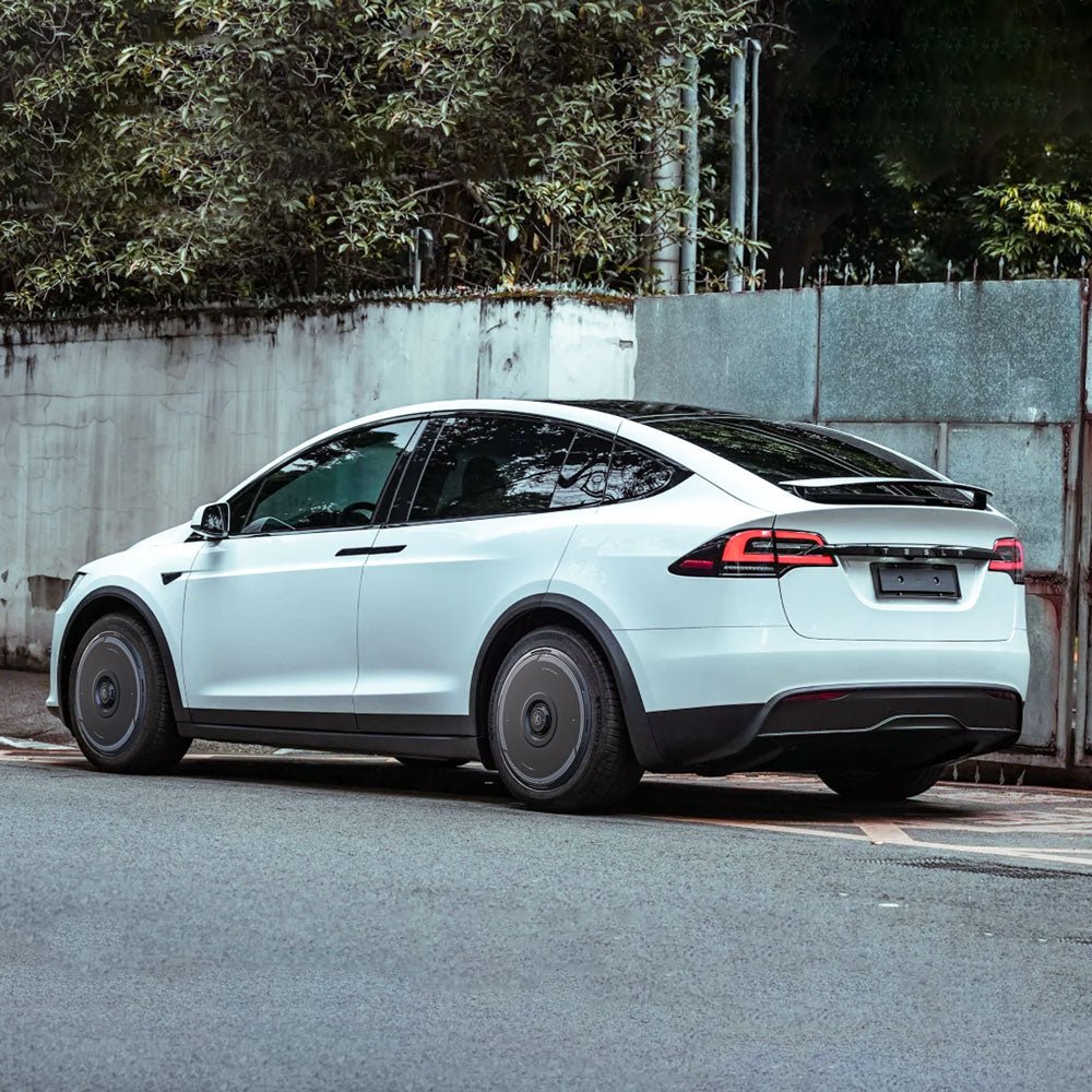 A white Tesla Model X (2016-2020) with 20" Slipstream wheels is parked by a concrete wall with greenery, featuring HALODISC 2 Wheel Covers from HALOBLK Store. The rear and left side of the SUV are visible.