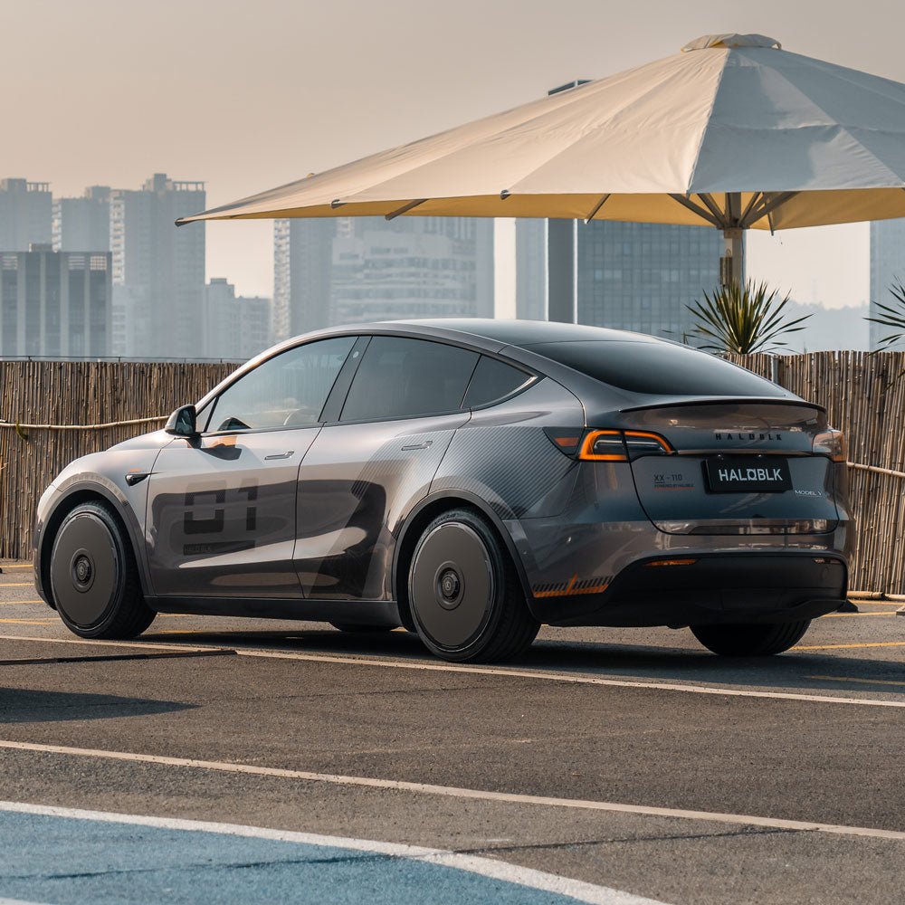 A Tesla Model Y with 21" Überturbine Wheels is parked on the road, featuring HALODISC 2 Wheel Covers by HALOBLK Store.