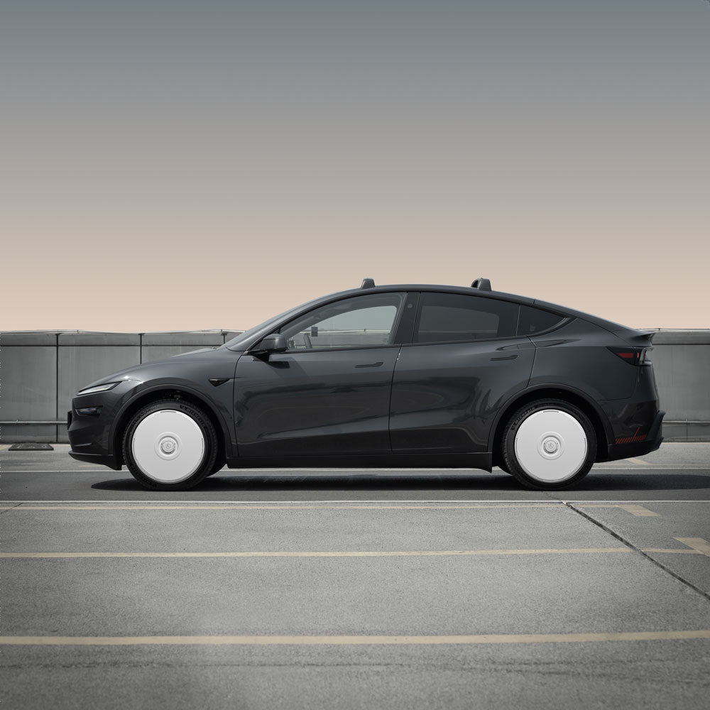 A black Tesla Model Y with HALODISC 2 Wheel Covers for Juniper 20" Helix 2.0 Wheels from HALOBLK Store is parked on an empty rooftop, set against a gradient sky shifting from beige to gray.