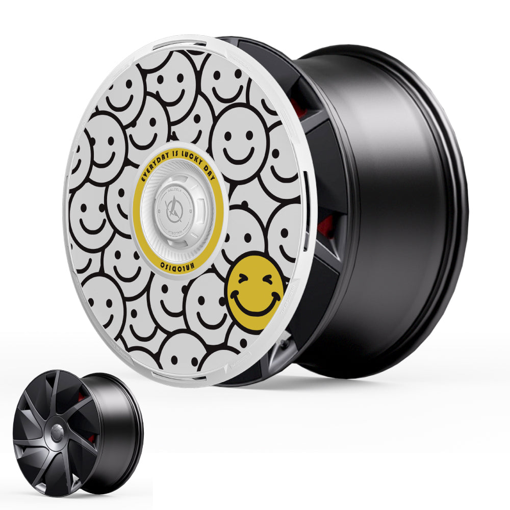 The HALODISC 2 Wheel Covers for Tesla Model S 21" Velarium Wheels by HALOBLK Store feature a hubcap with black-outlined smiling faces on a white background and a standout yellow smiley; a plain black rim is also shown for comparison.