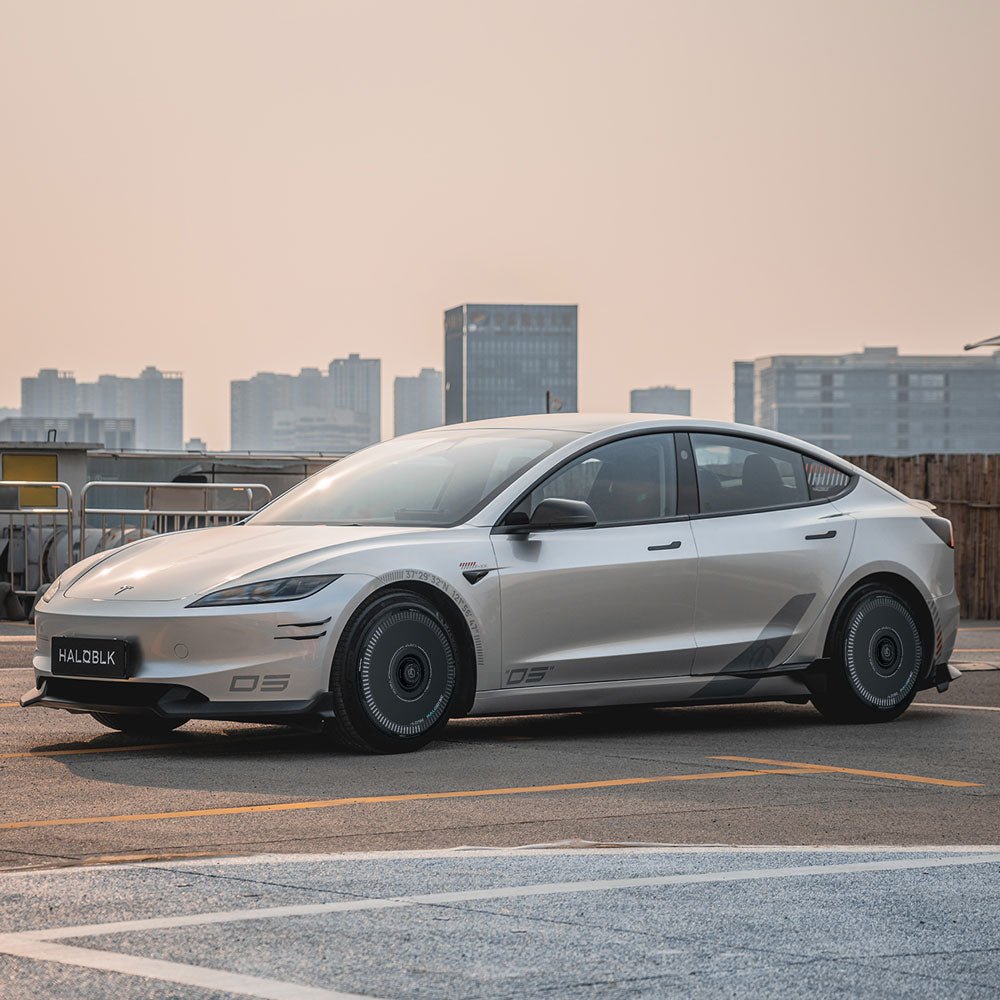 The HALODISC 2 Wheel Covers for Tesla Model 3 Highland 19" Nova Wheels by HALOBLK Store are showcased on a sleek silver electric sedan parked on an urban rooftop, with city buildings in the background under a pale sky.
