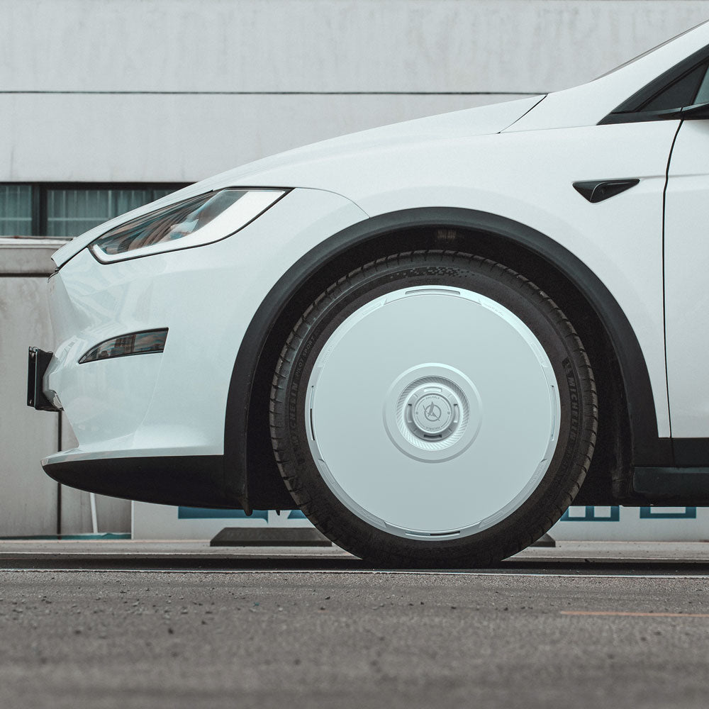 A close-up side view shows a Tesla Model X (2021-2025) with a shiny HALODISC 2 Wheel Cover by HALOBLK Store on its 20" Cyberstream front wheel, parked on the street in front of a white building with windows.