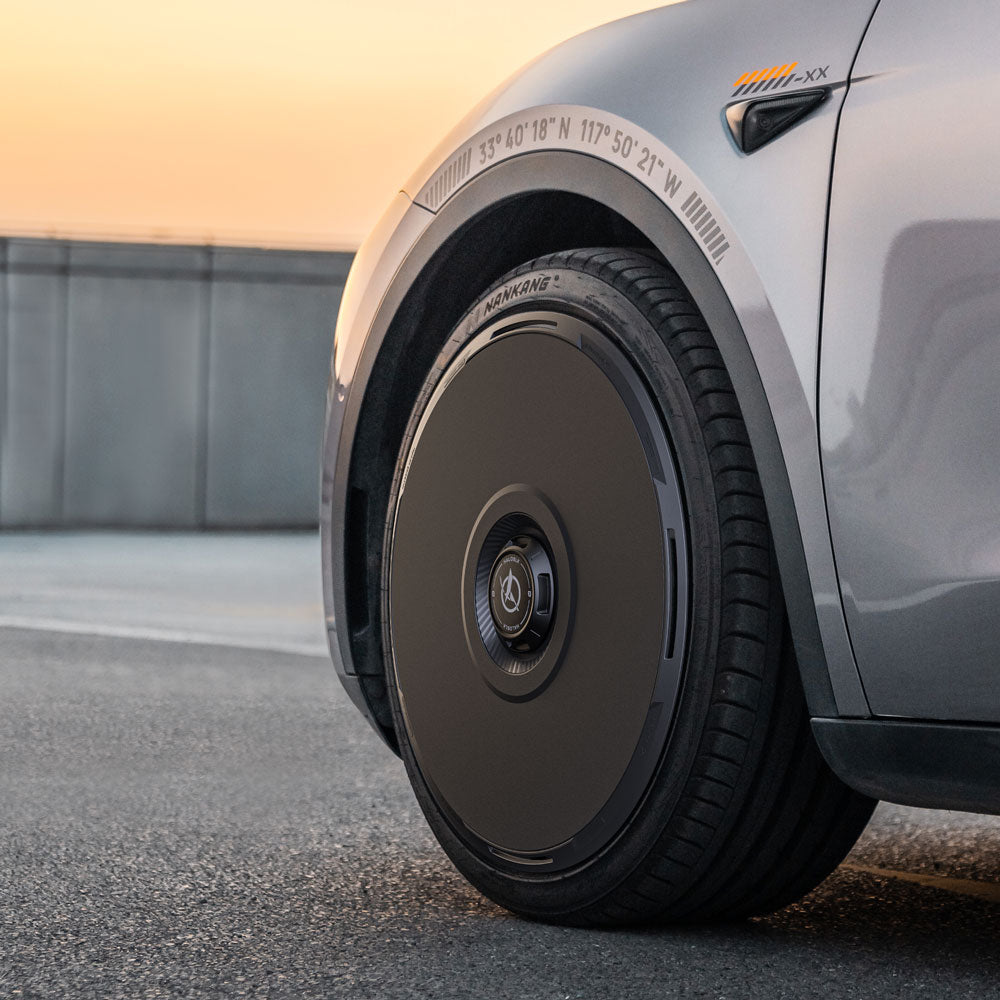 Close-up of HALODISC 2 Wheel Covers from HALOBLK Store, designed for Tesla Model Y 21" Überturbine Wheels. Features a sleek, solid black rim and minimalistic style, with calibration markings and coordinates on the silver fender above.