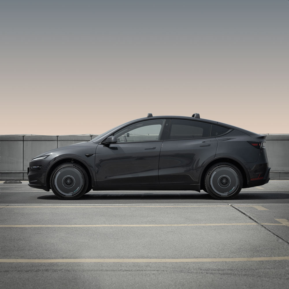 A Tesla Model Y with HALODISC 2 Wheel Covers for Juniper 20" Helix 2.0 Wheels from HALOBLK Store is parked outdoors by a low concrete barrier, under a clear sky.